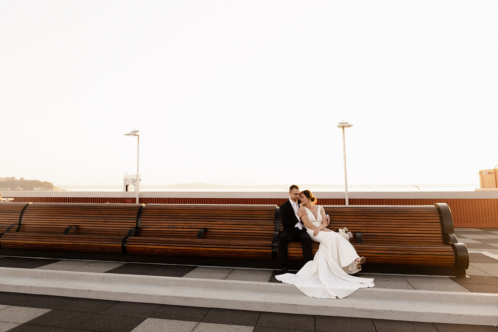 Wedding couple sitting together at sunset on a bench
