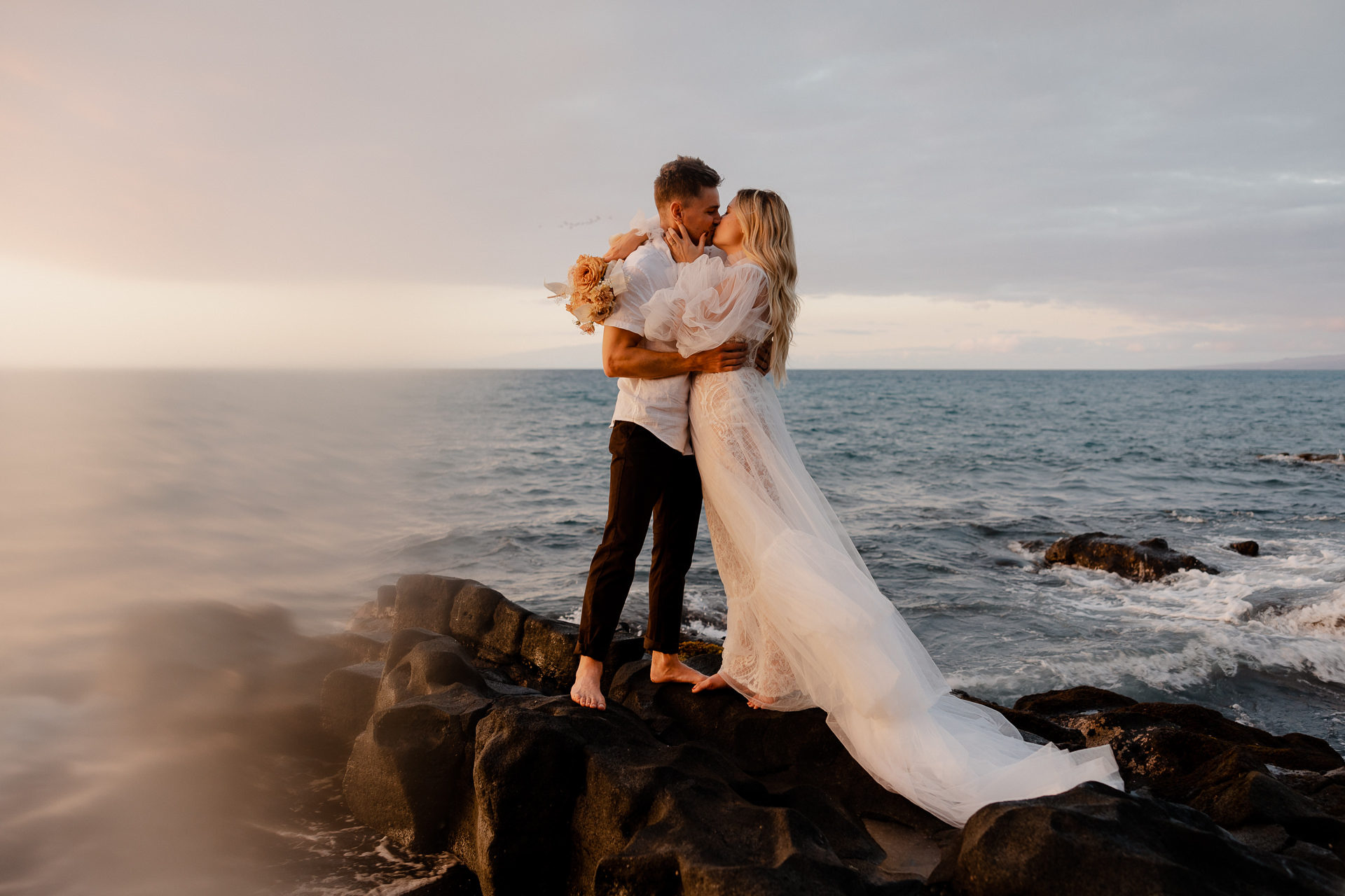 Couple kisses on black sand beach in hawaii