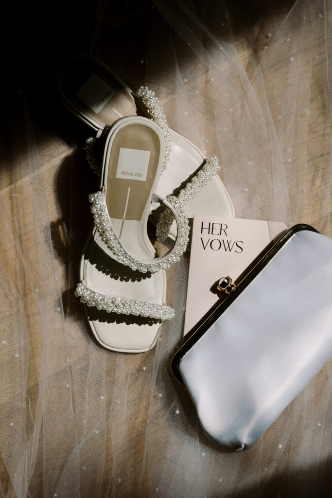 brides shoes lay next to vow book and purse